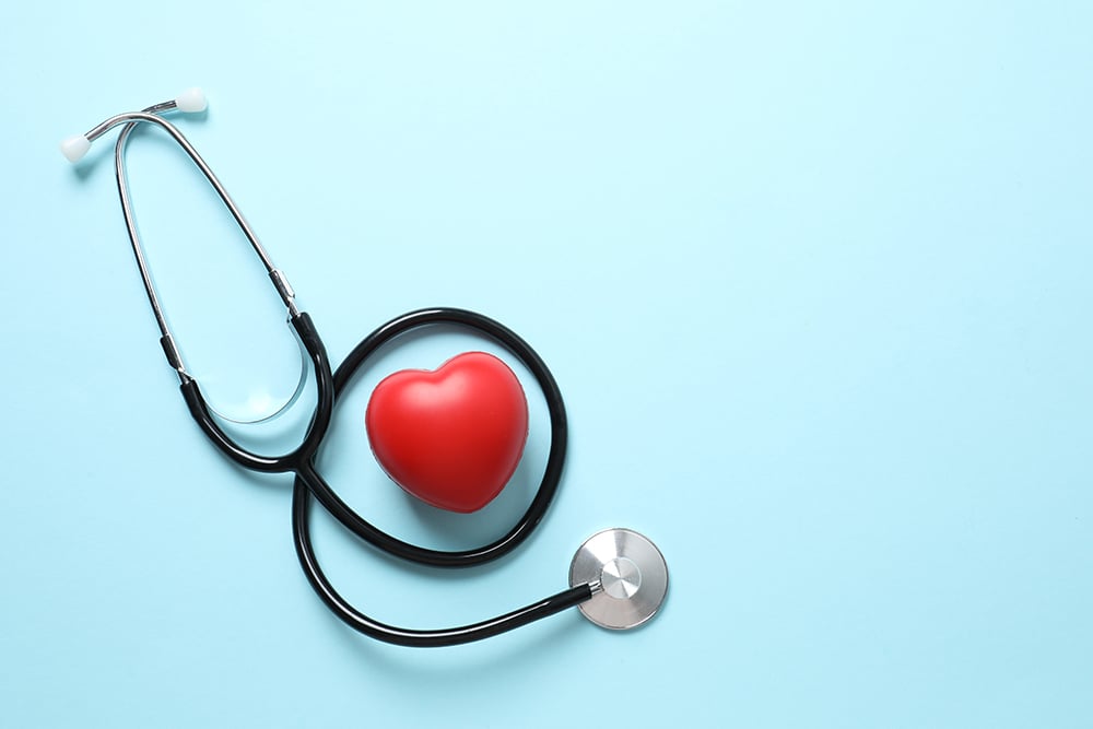 Stéthoscope avec un cœur rouge sur fond bleu, vue de dessus.